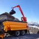 Camion benne avec bras de grue au travail.